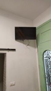 uma televisão pendurada numa parede ao lado de uma porta em Alzira bonita Habitación verde con baño privado em Alzira