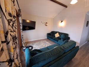 a living room with a blue couch and a tv at River Retreat - Norfolk Broads in Brundall