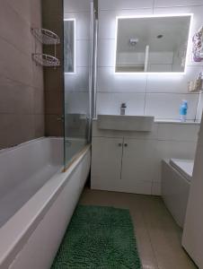 a bathroom with a tub and a sink and a green rug at 1 Bed Apartment Near Vibrant Bethnal Green in London