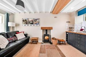 a living room with a black leather couch and a wood stove at Finest Retreats - Tyg Cottage in Ripon