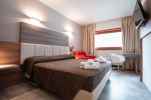 ピエトラムラタにあるHotel Ciclaminoのベッドと赤い椅子が備わるホテルルームです。