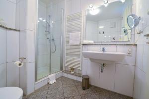een witte badkamer met een wastafel en een douche bij Strandpalais PE08 in Cuxhaven