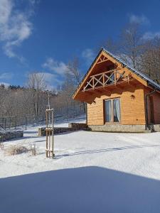 a log cabin in the snow with a fence at Domek w Górach Bardzkich in Kamieniec Ząbkowicki