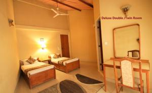 Habitación de hotel con 2 camas y espejo en Baghmara Wildlife Resort, en Sauraha