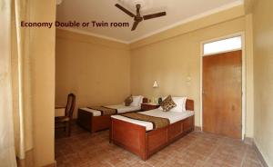 a bedroom with two beds and a ceiling fan at Baghmara Wildlife Resort in Sauraha