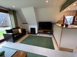 a living room with a couch and a television at Caledonia Lodge in Spean Bridge