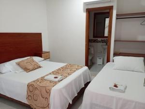 Habitación de hotel con 2 camas y aseo en HOTEL COSTA DEL SOL mav, en Turbo