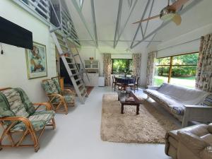 uma sala de estar com um sofá, cadeiras e uma mesa em Beautiful garden cottage em Stormsrivier