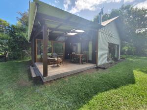 a house with a deck with a table and chairs at Beautiful garden cottage in Stormsrivier