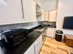 a kitchen with white cabinets and a black counter top at Spacious 2 bedroom apartment in London