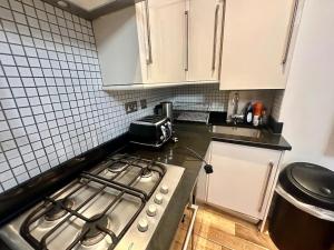 cocina con fogones y armarios blancos en Spacious 2 bedroom apartment, en Londres