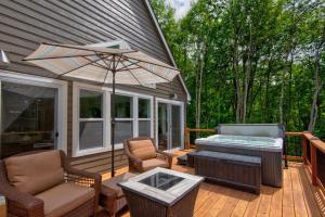 a deck with a hot tub and chairs and an umbrella at Lessons from Mars in Banner Elk