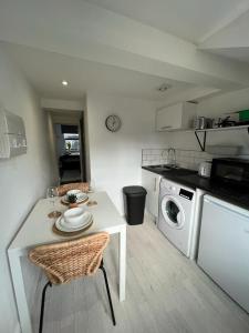 Guest Homes - Eign Street Apartments في هيريفورد: مطبخ مع طاولة بيضاء وكراسي وغسالة ملابس