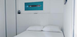 uma cama branca com duas almofadas e uma fotografia em Melhor localização em Boa Viagem! em Recife mais 27 fotografias