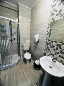 uma casa de banho com um lavatório, um WC e um chuveiro em Hotel Suprem em Băile Olăneşti