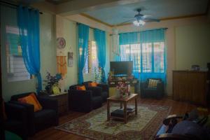 sala de estar con cortinas azules y TV en RnE Hometel Batanes, en Ivana