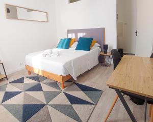 Un dormitorio con una cama con almohadas azules y una mesa. en Artbleu -Tout Confort - Idéal Pros - Proche commerces en Montluçon