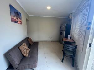 uma sala de estar com um sofá, uma mesa e um frigorífico em Suite Junior Urdesa Central. em Guayaquil