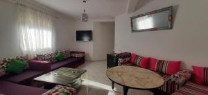 una sala de estar con sofás morados y una mesa. en APPARTEMENT AL HOCEIMA prés de PLAGE CALABONITA, en Alhucemas