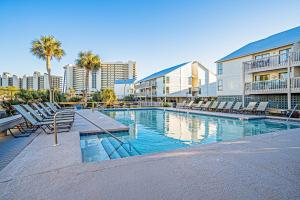 a swimming pool with chairs and palm trees and buildings at Cotton Bayou B1 in Orange Beach