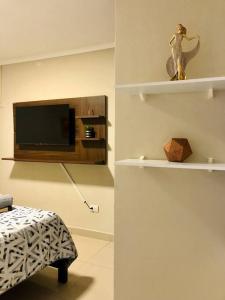 um quarto com uma televisão e uma estátua de um pássaro nas prateleiras em Suite Junior Urdesa Central. em Guayaquil