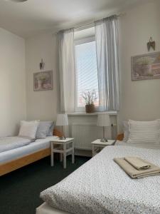 1 dormitorio con 2 camas y ventana en Penzion Ječmínek, en Luhačovice