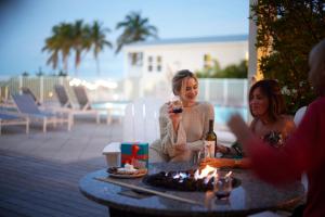 two women sitting at a table with a bottle of wine at Courtyard by Marriott Faro Blanco Resort in Marathon