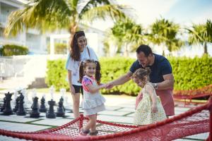 Um homem e duas raparigas a jogar xadrez num tabuleiro de xadrez gigante. em Courtyard by Marriott Faro Blanco Resort em Marathon