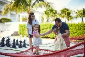 un hombre y dos chicas jugando ajedrez en un tablero de ajedrez gigante en Courtyard by Marriott Faro Blanco Resort, en Marathon