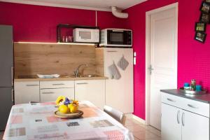 a kitchen with pink walls and a table with fruit on it at Maison Tifaloc in Montélimar