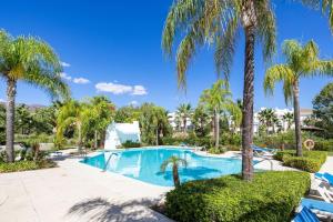 einen Pool mit Palmen in einem Resort in der Unterkunft Alcazaba Lagoon modern flat Ref M14 in Estepona