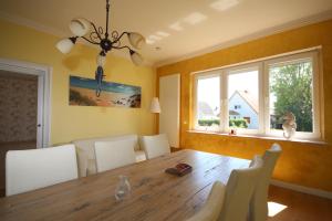 ein Esszimmer mit einem Holztisch und weißen Stühlen in der Unterkunft Villa Rosengarten auf der Sonneninsel Fehmarn in Fehmarn