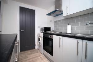 a kitchen with white cabinets and a black door at skyline hanover 2 bedroom 203 in Swansea