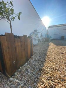 uma bicicleta estacionada ao lado de uma cerca e uma árvore em Villa avec jacuzzi proche de la mer et du centre em Barbâtre