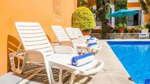 a group of white lounge chairs next to a swimming pool at Hotel Oaxaca Dorado in Oaxaca City