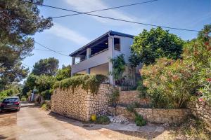 a house with a stone wall next to a car at Ivka 2 in Mali Lošinj