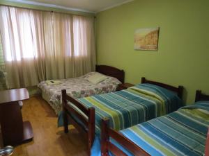 2 camas en una habitación con paredes verdes en Palm Hostal, en Iquique