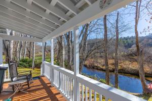 une terrasse couverte avec une chaise et une vue sur la rivière dans l'établissement Linville River Cottage, à Linville Falls