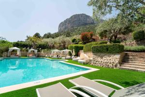 a swimming pool with chairs and a mountain in the background at Hotel Rural S'Olivaret & Spa in Alaró