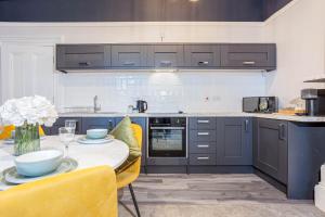a kitchen with blue cabinets and a table with yellow chairs at Coppergate Mews Grimsby No.1 - 2 bed, 2 bath, ground floor apartment in Grimsby