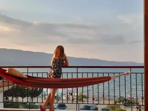 Una mujer parada en un balcón con vistas al agua en Dimitra House en Stavros