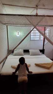 a person sitting on a large bed in a room at 2 Bed House - Sleeps 3 - Pool - Parking - Wifi in Ukunda