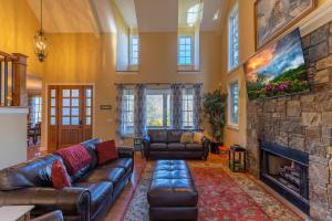 a living room with leather furniture and a stone fireplace at Pisgah Retreat at Linville Falls in Linville Falls