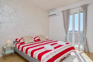 a bedroom with a bed with a red and white striped blanket at Apartment Piano in Dubrovnik