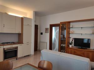 Il comprend une cuisine avec des placards blancs, un canapé et une télévision. dans l'établissement Casa Crispi, à Chioggia
