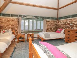 Cette chambre comprend 3 lits et un mur en briques. dans l'établissement 1 Alston Farm Cottages, à Brixham