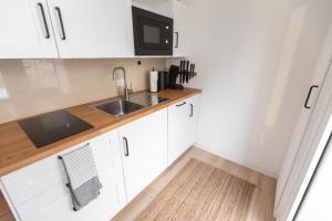 eine Küche mit weißen Schränken und einem Waschbecken in der Unterkunft Koje Fünf I Apartment in Stadtmitte mit Hafenblick in Bremerhaven