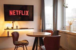 a table and chairs in a room with a netflix sign at Koje Fünf I Apartment in Stadtmitte mit Hafenblick in Bremerhaven