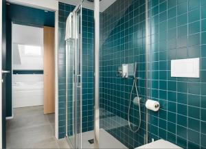 un bagno con doccia in vetro con piastrelle blu di Design Attic porta venezia centrale 65m2 - self check-in a Milano Altre 7 foto