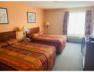 a hotel room with two beds and a window at Aurora Park Inn & Suites in Dawson Creek